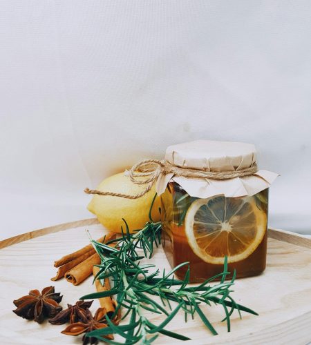 Artistic arrangement of lemon, herbs, and honey jar for DIY herbal tea.